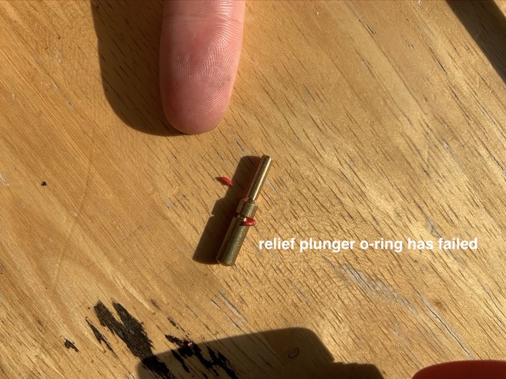 photo showing the brass cyliner with the broken o-ring partially wrapped around it. text on image: relief plunger o-ring has failed