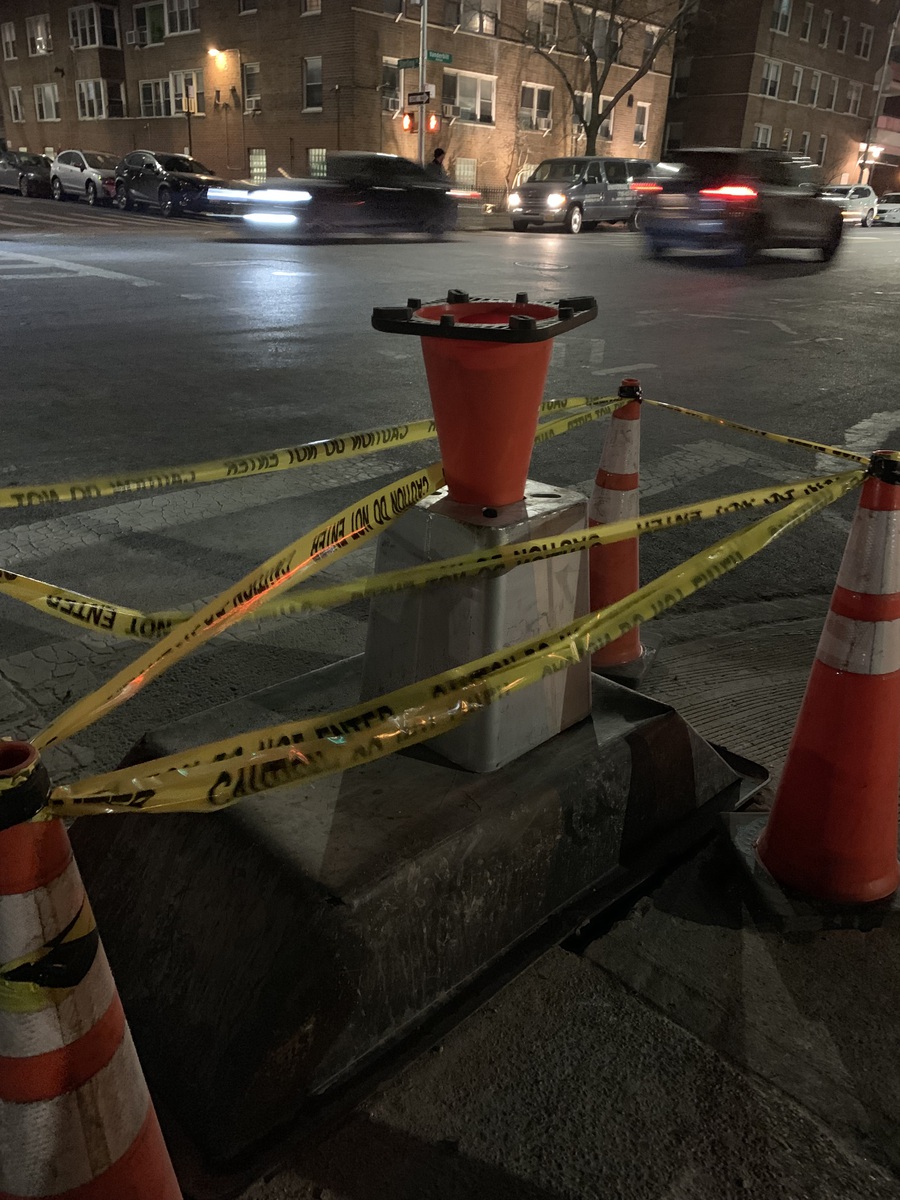 An orange safety cone inverted and placed into the open hole of a street lamp base.